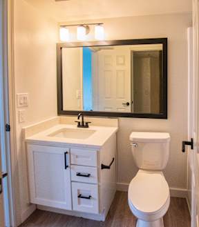 A white toilet sits under a mirror in a bathroom.