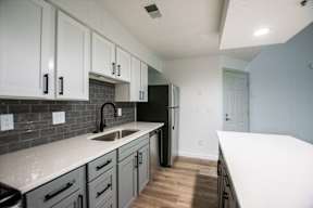 A kitchen with white cabinets and a black refrigerator.