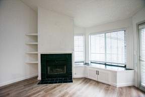 A white room with a fireplace and wooden floors.