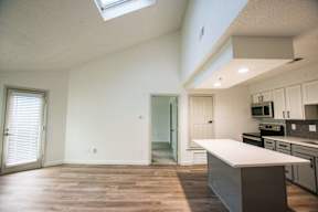 A kitchen with a skylight and wooden floors.