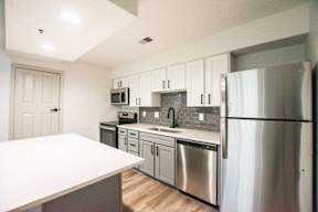 A kitchen with a white counter top and stainless steel appliances.