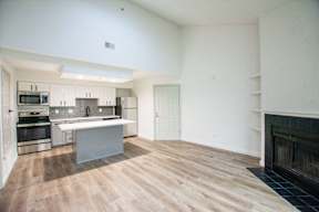A modern kitchen with wooden floors and a fireplace.