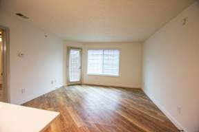 A room with wooden floors and a window with blinds.