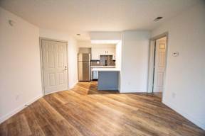 A kitchen with a refrigerator, sink, and cabinets is visible through a doorway.