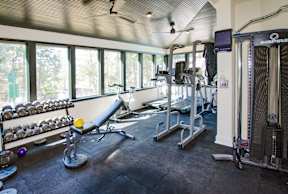 A gym with a row of dumbbells on the left and a row of exercise machines on the right.
