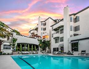 A large white building with a pool in front of it.