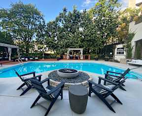 A pool with four chairs around a fire pit.
