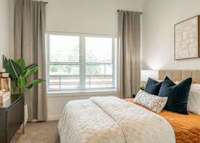 A bedroom with a large bed and a window with curtains.