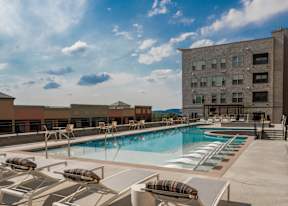 A pool with sun loungers and a building in the background.