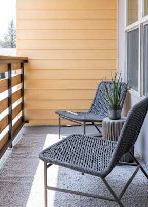 A patio with two chairs and a table with a plant on it.
