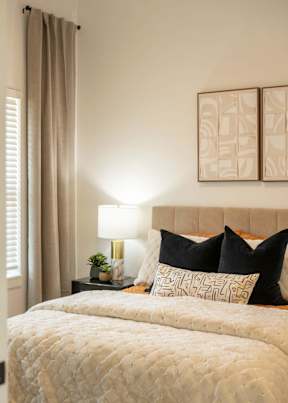 A bed with a white comforter and a lamp on a side table.