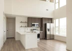 A modern kitchen with white countertops and stainless steel appliances.