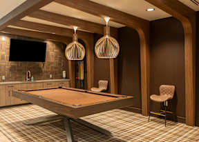 A pool table in a room with wooden walls and a chair.