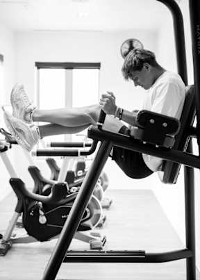A man is working out on a leg press machine in a gym.