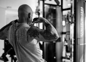 A man with a tattoo on his back is working out in a gym.