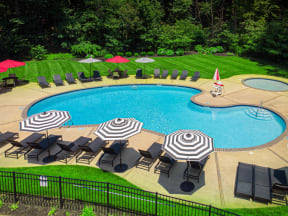 a swimming pool with umbrellas and chairs around it at Atlantic Pointe Apartments, Atlantic Highlands