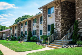 a rendering of the front of a brick building with stairs and grass at Atlantic Pointe Apartments, New Jersey, 07716