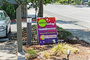 A sign for Timberwood is placed on the side of a road.