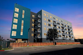 A modern apartment building with a parking lot in front.