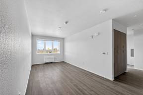 A spacious room with wooden flooring and a large window.