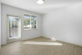 A room with a white wall and a window with blinds.