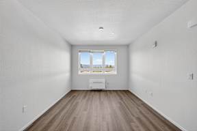 A room with a window and a white fridge.