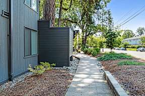 A modern house with a grey exterior and a small garden in front.