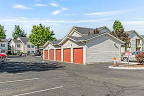 A parking lot with a building and a tree in the background.