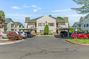 A parking lot in front of a building with cars parked.