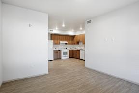A kitchen with white walls and wooden floors.