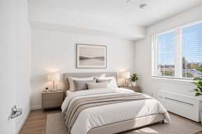 A well-lit bedroom with a large bed and a framed picture on the wall.