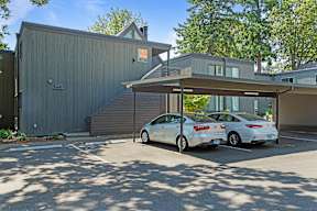 A white car is parked in front of a grey building.