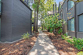 A pathway leads through a landscaped area between two buildings.