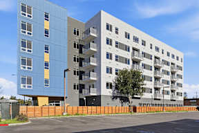 A modern apartment building with a parking lot in front.