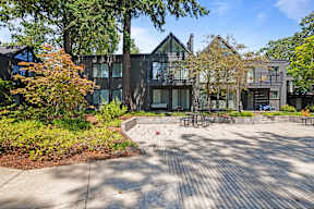 A modern building with a black exterior and a large courtyard with a picnic table.