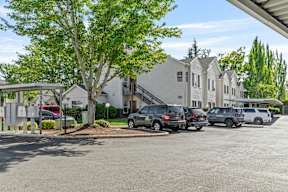 A parking lot with cars and a building in the background.