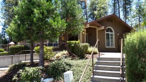 a brown house with stairs and trees in front of it