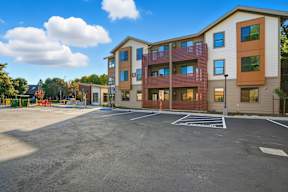 A parking lot in front of a multi-story apartment building.