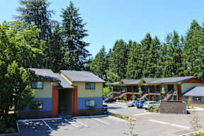 A parking lot in front of a yellow building with a red door.