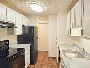 A kitchen with black appliances and white cabinets.