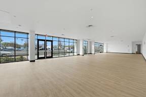 A large, empty room with wooden floors and large windows.