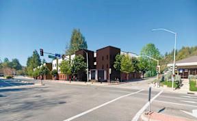 A street view of a city intersection with traffic lights and buildings.