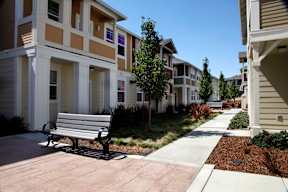 a park bench sits in front of a row of apartment buildings