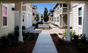 a bench sits in the middle of a sidewalk in front of an apartment building