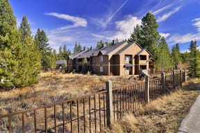a house in the woods with a fence in front of it