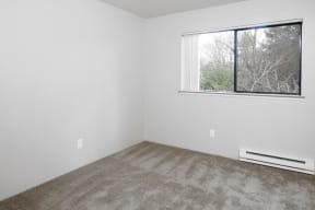 a bedroom with a large window and white walls