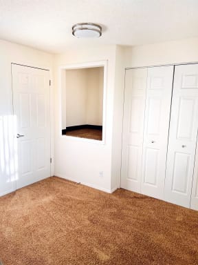 an empty room with a carpeted floor and white closets