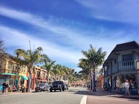 A street scene with cars and palm trees.