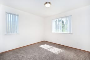 an empty room with carpet and two windows