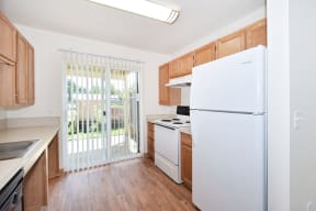 a kitchen with a white refrigerator and a sliding glass door